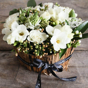 White roses and freesias in a bark container