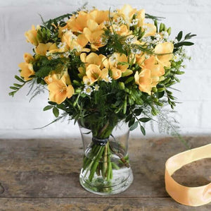 yellow freesias in a glass vase