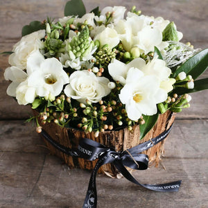 white roses and freesias in a container