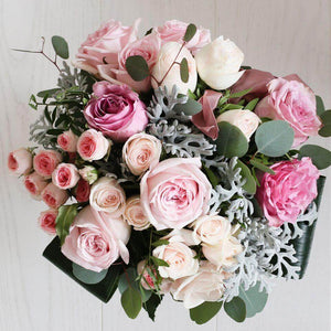 a variety of pink roses and foliage in a bouquet.