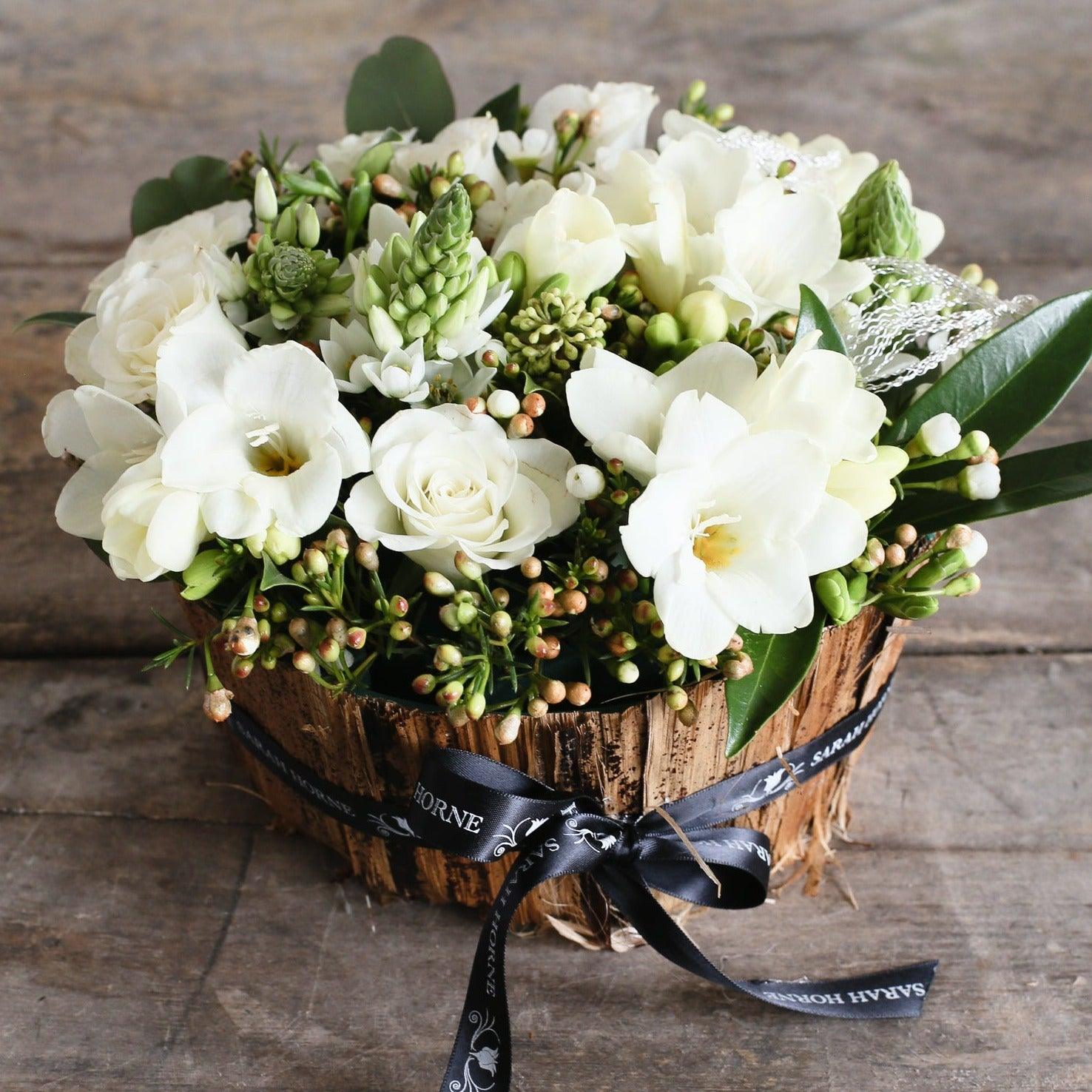 a banana bark bowl arranged with white flowers and foliage