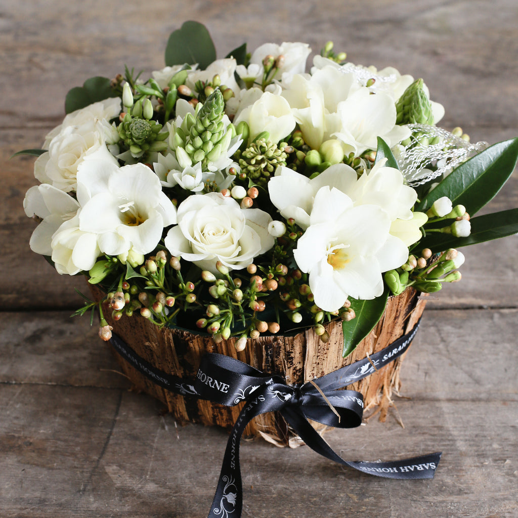 a banana bark bowl arranged with white flowers and foliage