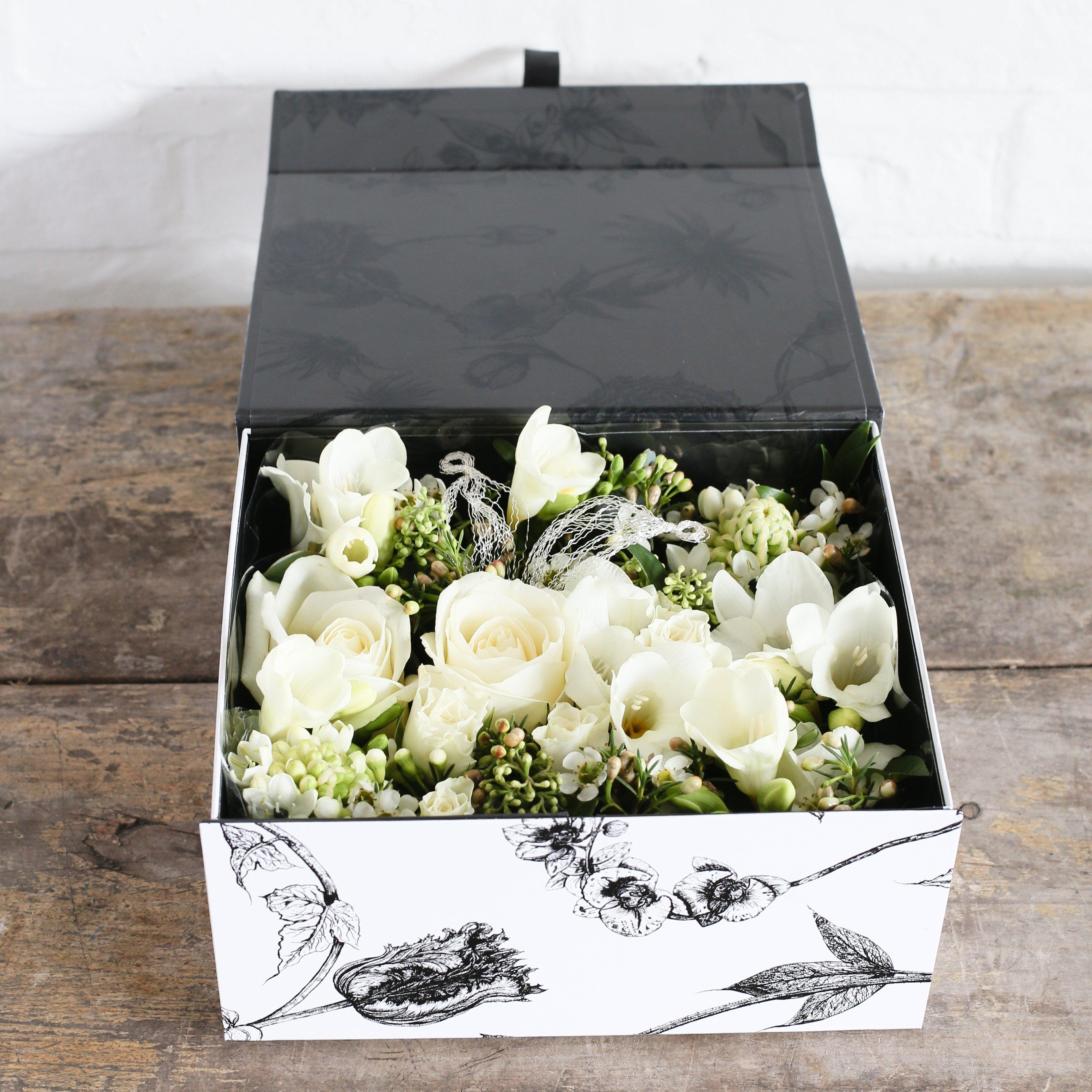a beautiful printed box full of white roses and freesia