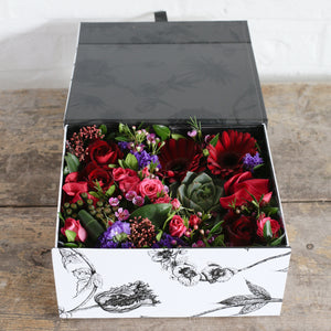 Red and purple flowers and foliage in a gift box