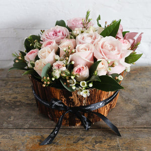 pink Pink roses of various head sizes in a bark bowl.