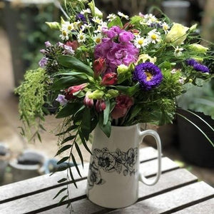 an orchid design jug full of purple and and lilac seasonal flowers