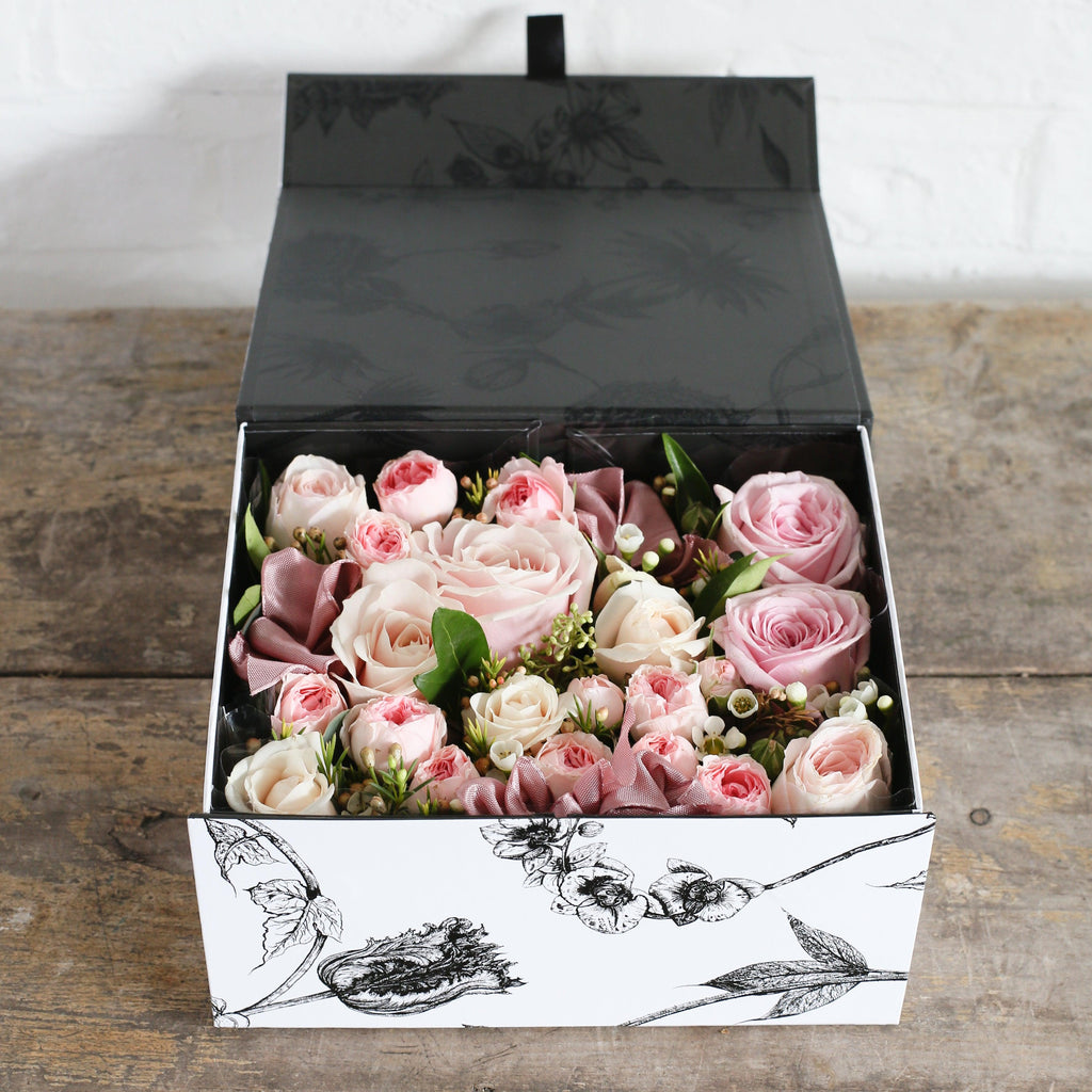 A Botanical design gift box filled with pastel pink roses.