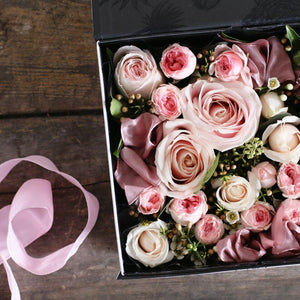 Pastel pink roses and foliage in a gift box