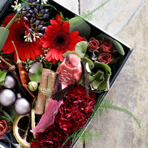 Red roses and carnations berries and baubles in a gift box