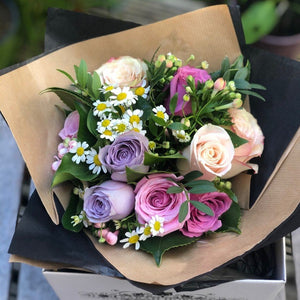 A petite hand-tied of pastel roses and foliage.