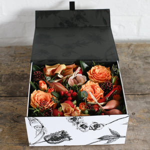 A Botanical design gift box full of orange flowers and vegatables. 