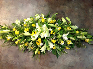 White lilies, freesia and yellow roses in a coffin spray