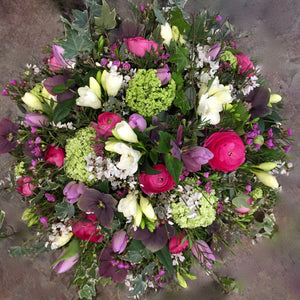 cerise ranunculus, white freesia , lilac tulips and foliage in a funeral posy.