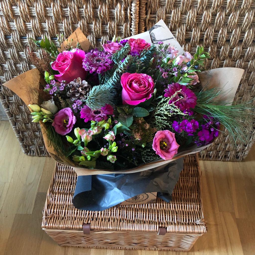 pink roses and purples flowers sprinkled with glitter in a hand tied box