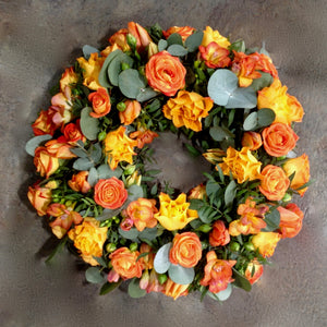 Amber and copper coloured roses with orange freesia in funeral wreath