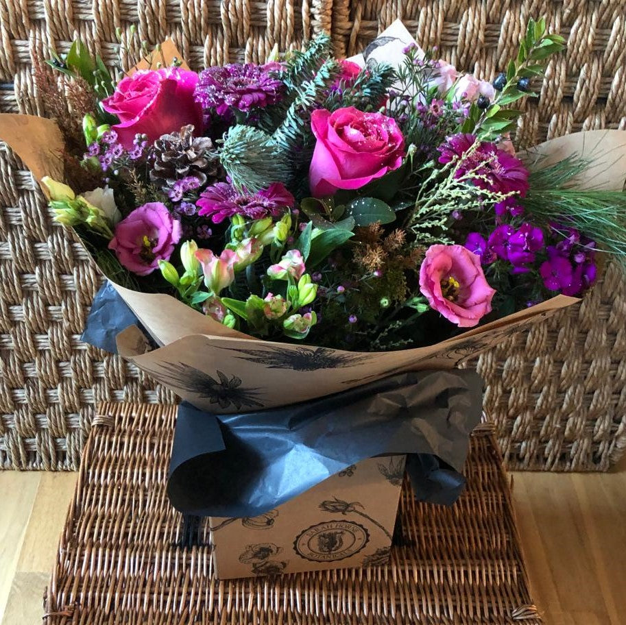 pink roses and purples flowers sprinkled with glitter in a hand tied box