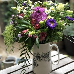a jug with orchid design filled with seasonal flowers
